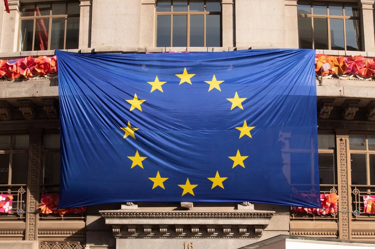 A European Union flag draped across the facade of a classical institutional building, representing the EU-wide scope of the Cyber Resilience Act